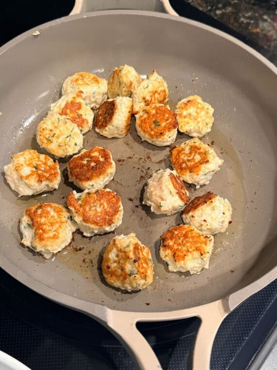 Browning meatballs in a skillet.