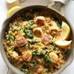 Lemon orzo in a skillet with chicken meatballs and a wooden serving spoon in the skillet