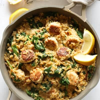 Lemon orzo in a skillet with chicken meatballs and a wooden serving spoon in the skillet
