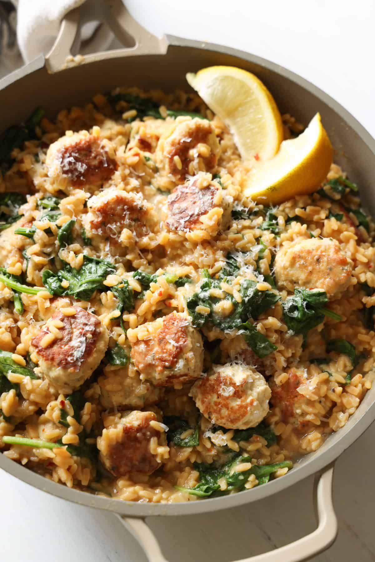 Chicken meatballs with lemon spinach orzo in a skillet