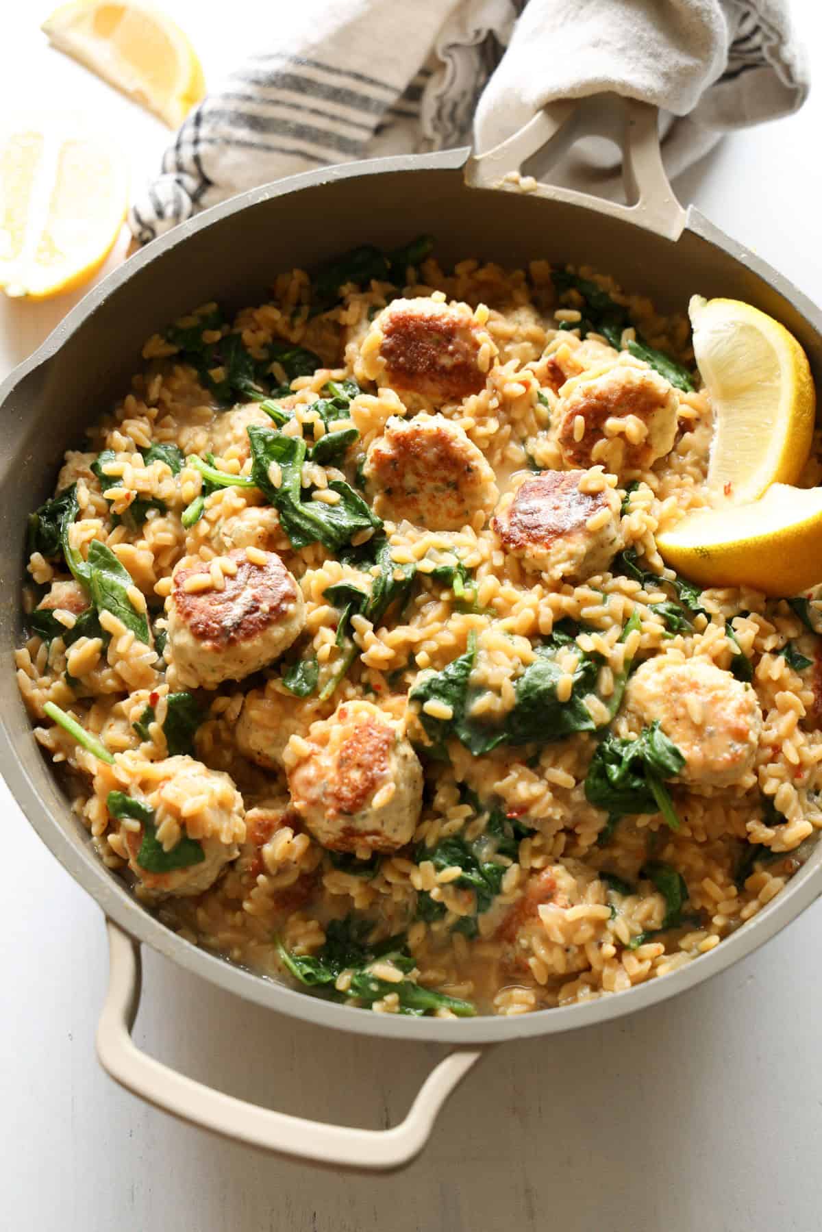 Chicken meatballs in an skillet with orzo and spinach