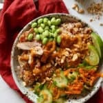 A high protein chicken bowl in a stone bowl drizzled with peanut sauce.