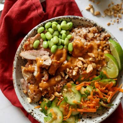 A high protein chicken bowl in a stone bowl drizzled with peanut sauce.