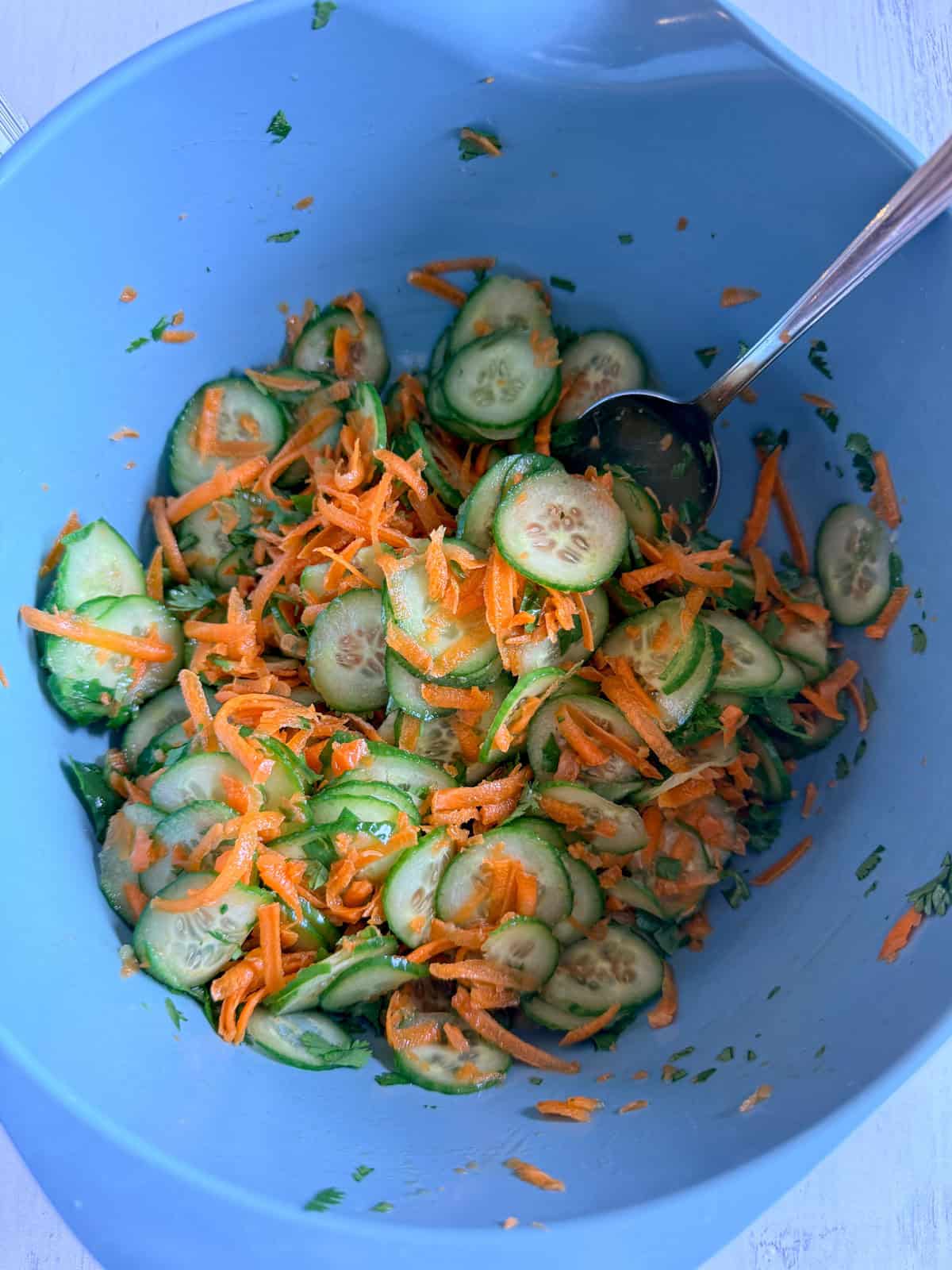 Cucumber carrot salad mixed together in a blue bowl.