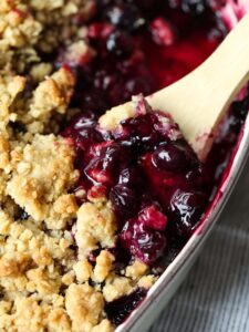 Blueberry Crisp in a baking dish with a spoon to serve