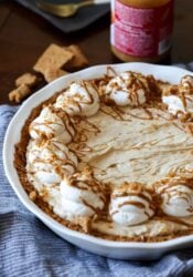 Cookie Butter pie in a white pie plate topped with whipped cream, crushed cookies, and drizzled Biscoff spread